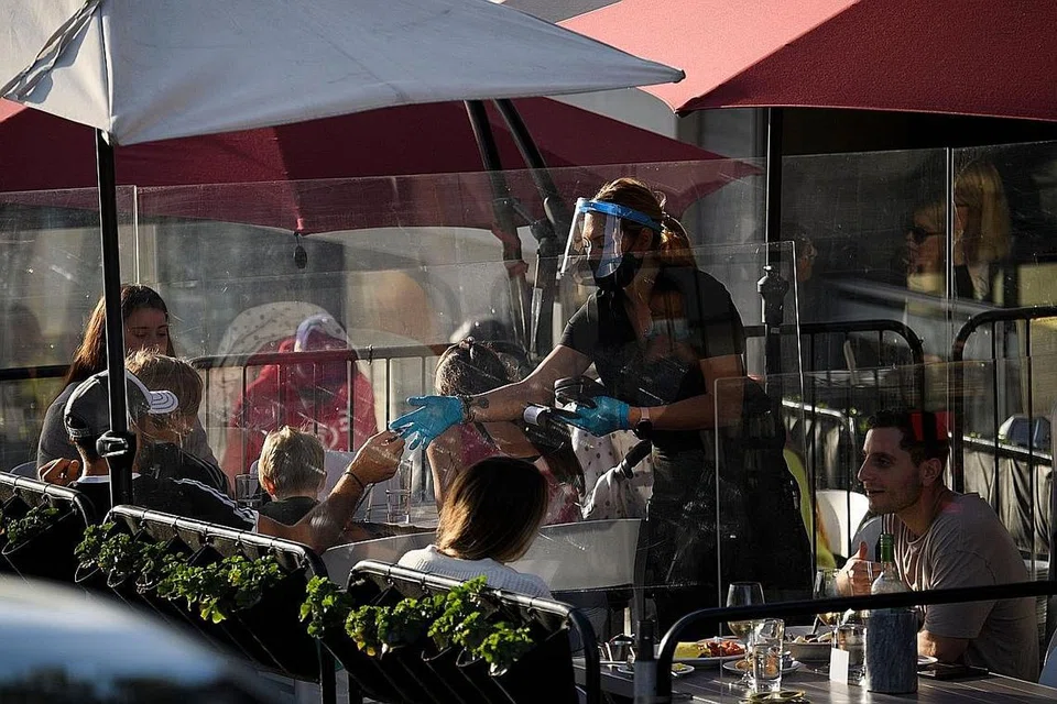 LINDUNGI DIRI: Seorang pelayan lengkap memakan sarung tangan dan pelindung muka serta pelitup di sebuah restoran di Manhattan Beach, California, semalam. Kes Covid-19 di Amerika Syarikat telah melepasi 12 juta semalam. - Foto AFP