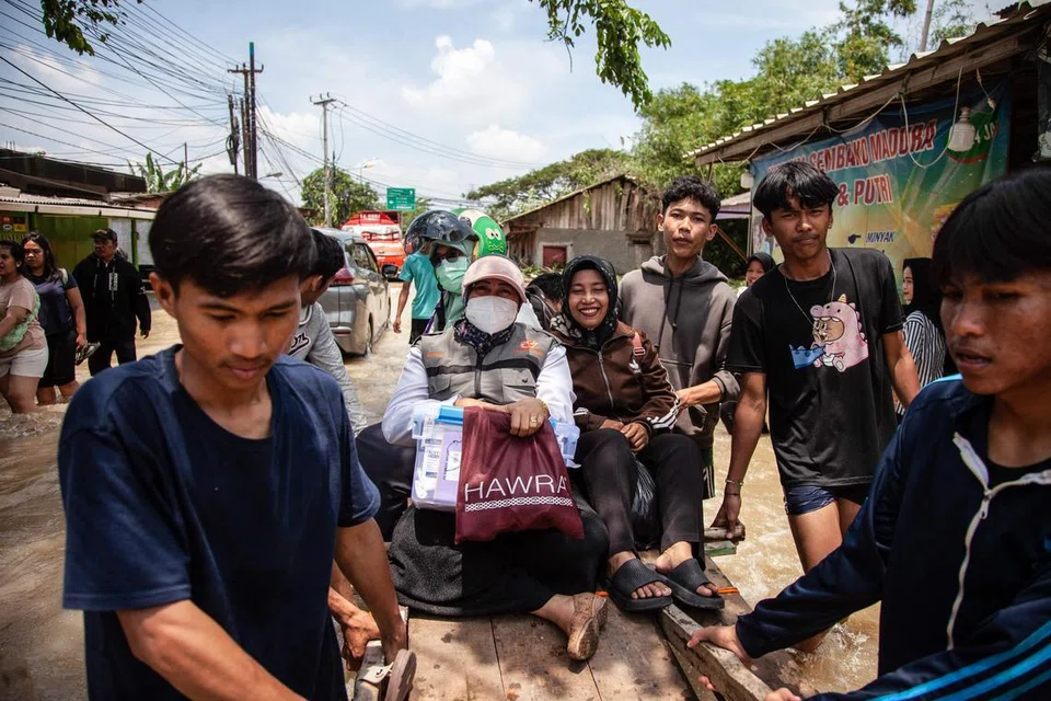 Sekumpulan penduduk menggunakan troli untuk meredah kawasan yang dilanda banjir selepas beberapa air sungai melimpah akibat hujan lebat di Bekasi, kawasan pinggir Jakarta, pada 5 Mac.