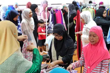 PILIHAN BAJU RAYA: Para penerima bantuan berpeluang memilih pakaian baju kurung terpakai untuk setiap seorang daripada anggota keluarganya. Mereka juga menerima habuan makanan kering, biskut Hari Raya selain wang tunai untuk perbelanjaan mereka. - Foto BH oleh GAVIN FOO