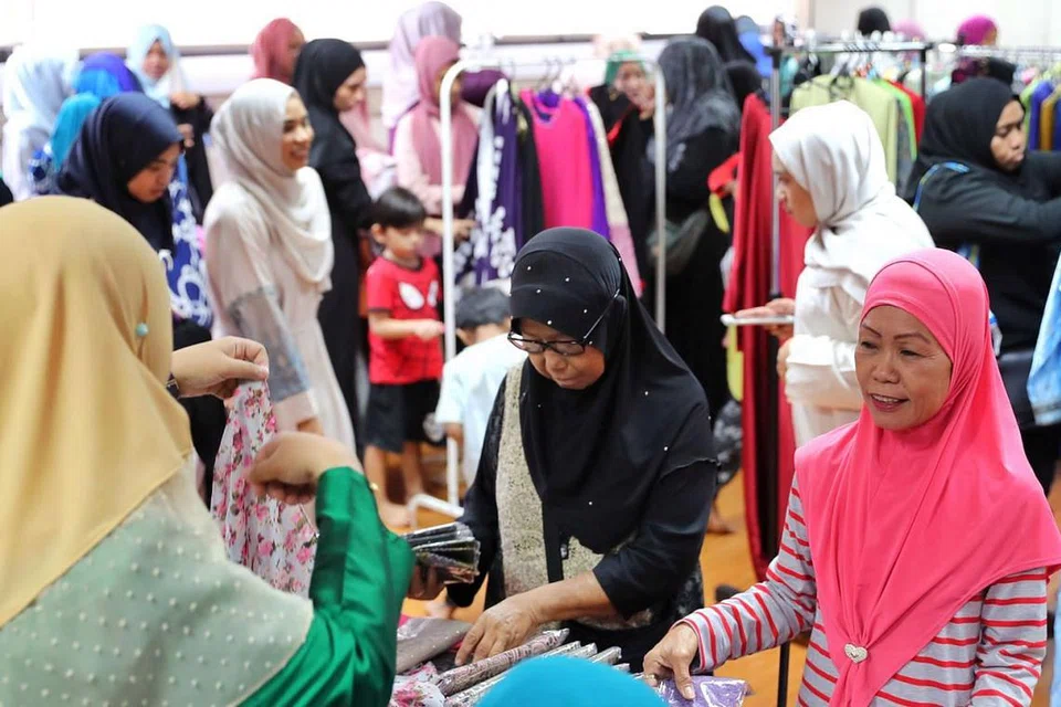 PILIHAN BAJU RAYA: Para penerima bantuan berpeluang memilih pakaian baju kurung terpakai untuk setiap seorang daripada anggota keluarganya. Mereka juga menerima habuan makanan kering, biskut Hari Raya selain wang tunai untuk perbelanjaan mereka. - Foto BH oleh GAVIN FOO