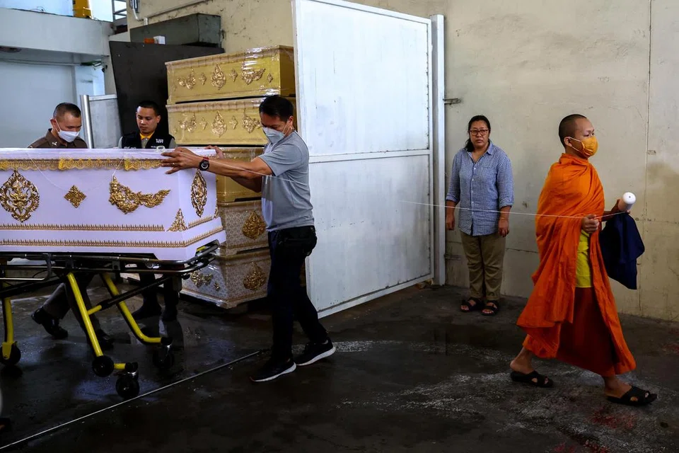 TRAGEDI MENYAYAT HATI: Seorang sami Buddha dan pegawai polis membawa keranda yang mengandungi mayat seorang mangsa dari Myanmar di Institut Sains Forensik Bangkok dalam. Warga Myanmar ini adalah antara dua mangsa yang terbunuh dalam insiden tembakan di pusat beli-belah Siam Paragon pada Selasa.