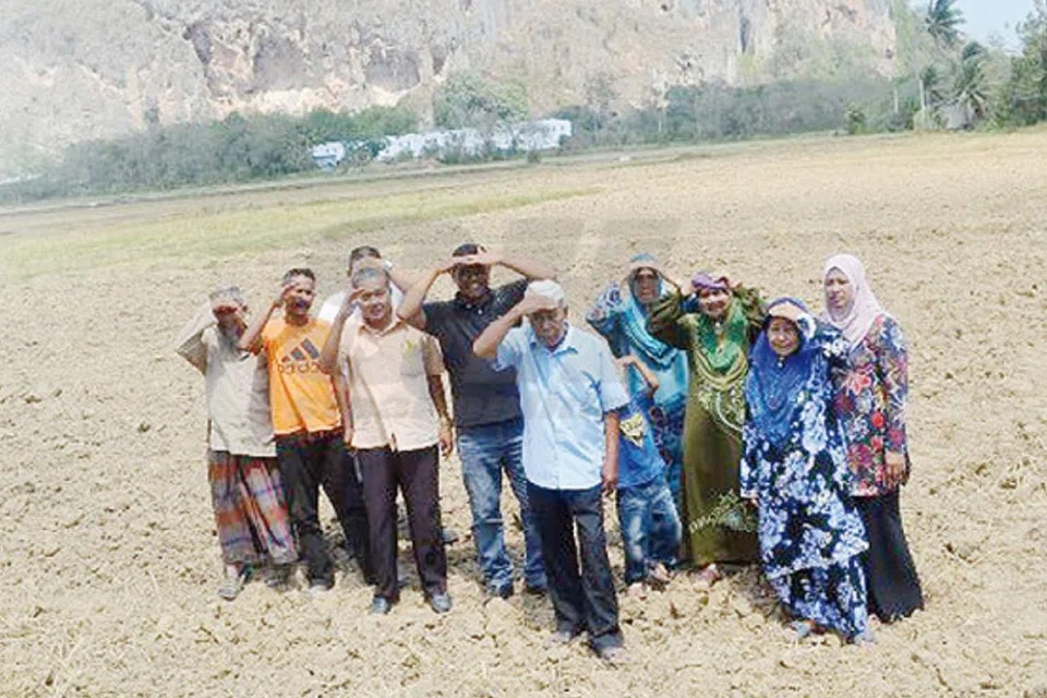 DIRI TENGAH PANAS: Penduduk kampung sekitar Bukit Chuping bergambar di bawah terik matahari berhadapan dengan Bukit Chuping yang kini gondol. - Foto SINAR HARIAN