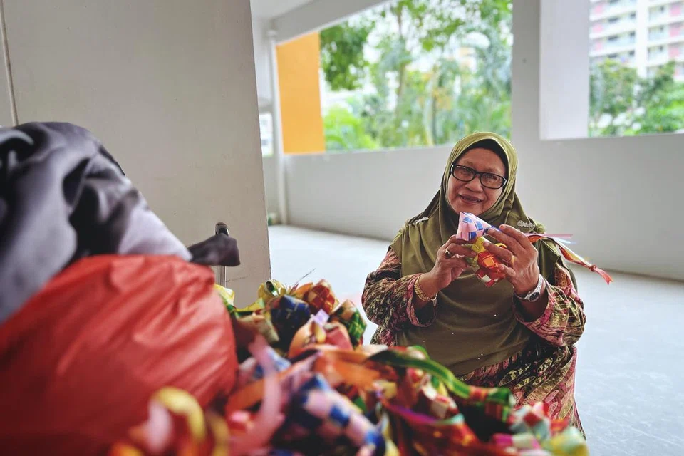 Cik Norinin Salleh, 74 tahun, kelihatan menyediakan hiasan ketupat berwarna-warni untuk digantung di kariah Blok 827A, Tampines Street 81.