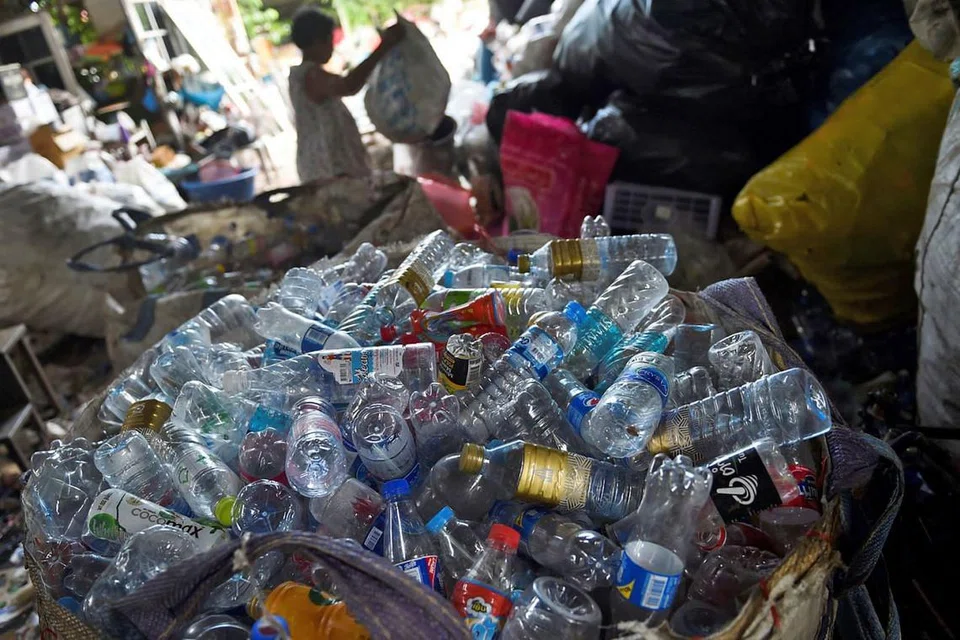 THAILAND: Seorang wanita menyusun sisa plastik di kedai sekerapnya di Bangkok. 