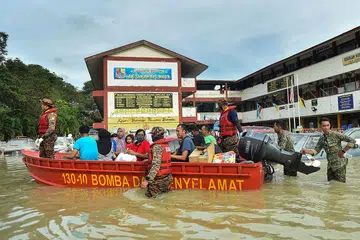 DILANDA BANJIR: Foto fail menunjukkan pegawai penyelamat memindahkan orang ramai dengan menggunakan bot di Shah Alam, Selangor, apabila banjir melanda Disember tahun lalu. Banjir dijangka lagi tahun ini apabila rakyat Malaysia keluar mengundi bulan depan. - Foto AFP