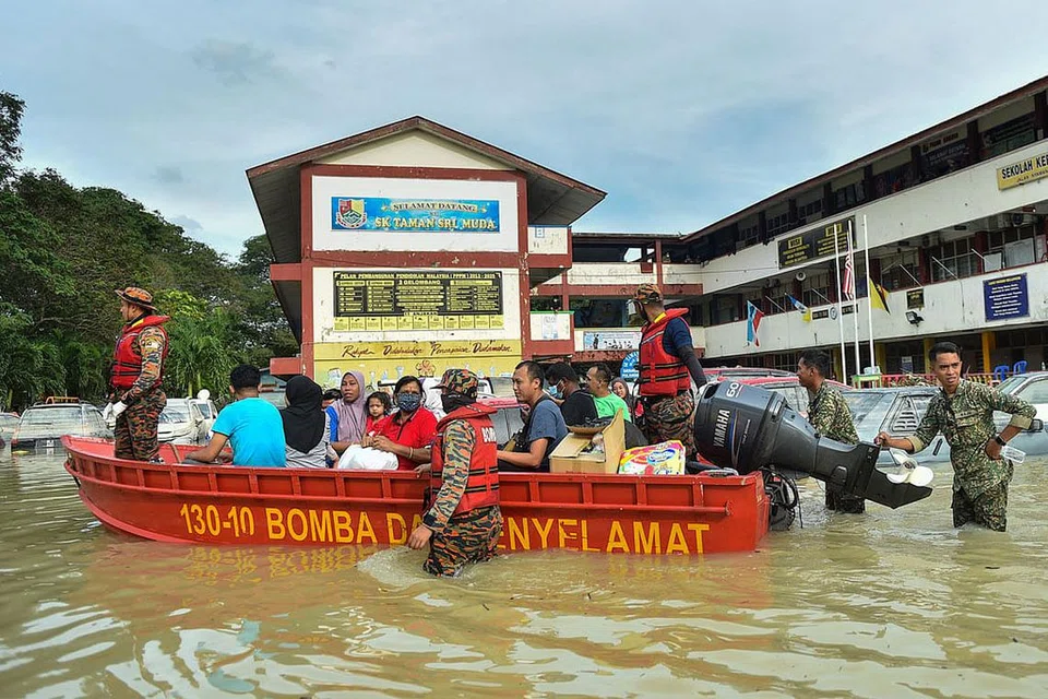 DILANDA BANJIR: Foto fail menunjukkan pegawai penyelamat memindahkan orang ramai dengan menggunakan bot di Shah Alam, Selangor, apabila banjir melanda Disember tahun lalu. Banjir dijangka lagi tahun ini apabila rakyat Malaysia keluar mengundi bulan depan. - Foto AFP