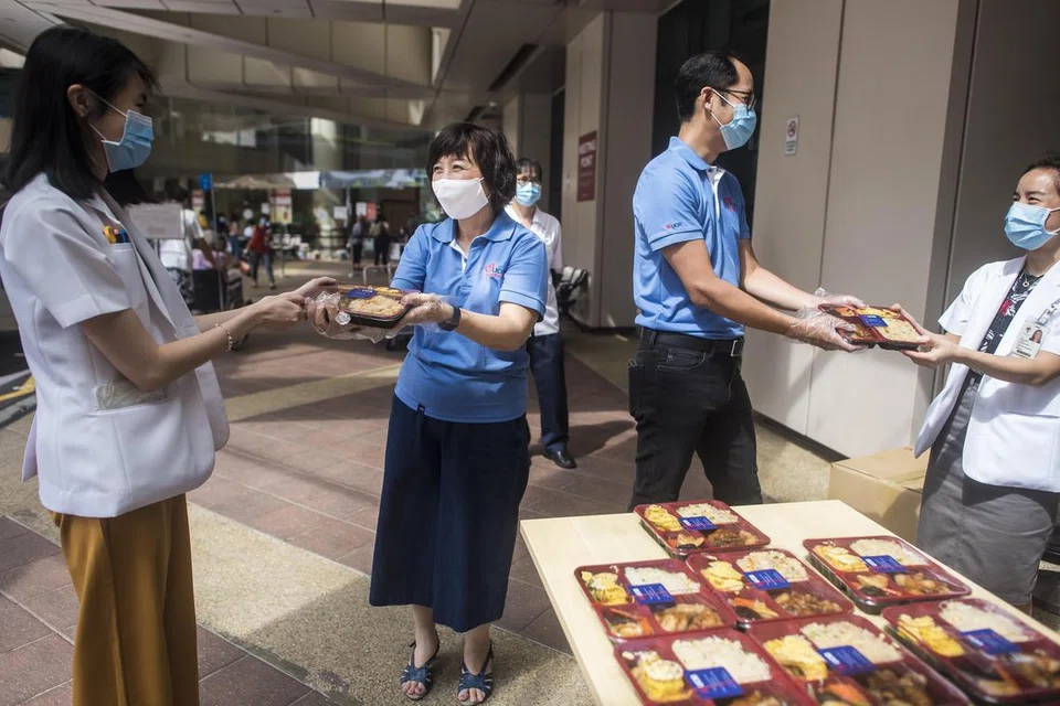 Para pekerja bank membahago-bahagikan makanan kepada petugas-petugas di barisan hadapan di Hospital  Tan Tock Seng Hospital semasa pandemik Covid-19. Gambar file