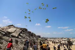 Penduduk Palestin berlari menuju ke arah payung terjun yang membawa bungkusan bantuan udara di utara Jaluran Gaza, 7 Ogos 2025