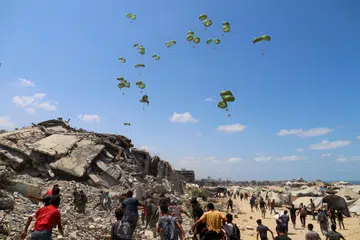 Penduduk Palestin berlari menuju ke arah payung terjun yang membawa bungkusan bantuan udara di utara Jaluran Gaza, 7 Ogos 2025