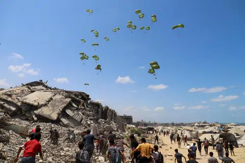 Penduduk Palestin berlari menuju ke arah payung terjun yang membawa bungkusan bantuan udara di utara Jaluran Gaza, 7 Ogos 2025