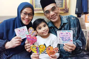 Muhammad Zafran bersama datuk dan neneknya bergambar dengan kad serta kraf origami yang dibuatnya. - Foto FAMILIES FOR LIFE