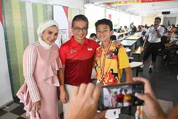 IMPI KE PIALA DUNIA: (Dari kanan) Mika bergambar bersama Encik Tong dan ibunya, Cik Norfasarie Mohd Yahya, dalam majlis pelancaran Akademi Bola Sepak Singapura di Sekolah Menengah Jurongville semalam. - Foto BH oleh LIM YAOHUI