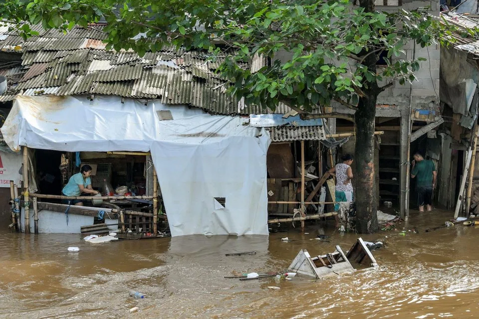 Seorang wanita (kiri) cuba mengalirkan air keluar dari dalam rumahnya apabila kawasan kejiranannya dilanda banjir susulan hujan lebat di Jakarta pada 7 Julai 2025