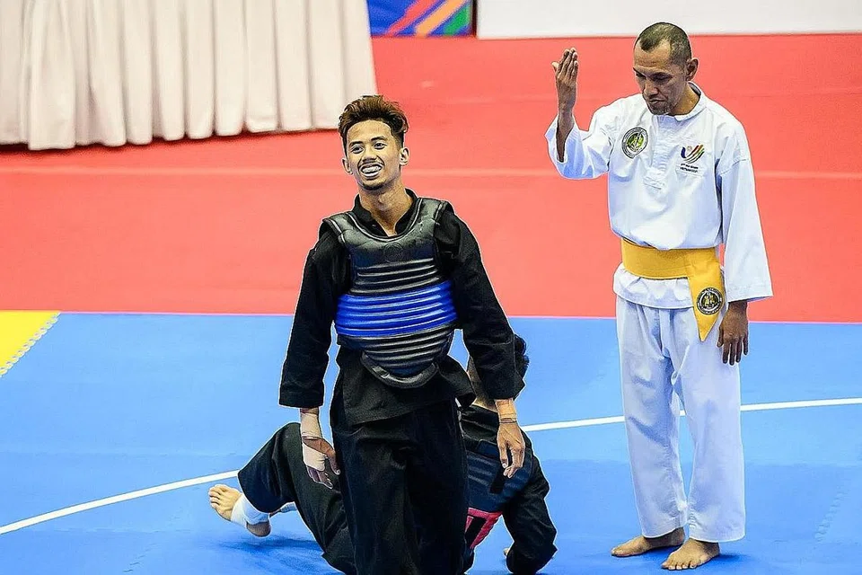 TERUS BERJUANG: Hazim (rompi biru) mengecewakan harapan tuan rumah, Vu Van Kien dari Vietnam, di Gimnasium Bac Tu Liem semalam, untuk mara ke separuh akhir tanding putera kelas C (55-60kg). - Foto SPORT SINGAPORE
