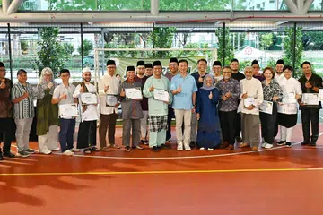 Encik Ong Ye Kung (berbaju biru di tengah), Cik Mariam Jaafar (bertudung biru di tengah) dan Encik Zalman Putra Ahmad Ali (sebelah Cik Mariam) bersama para penderma Kempen Amal Ramadan ‘Spirit of Sembawang’ M³@Woodlands.