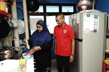 CARI REZEKI: Cik Suzanna Zainal dan suaminya, Encik Muhammad Hisham Dol, bersama-sama menjalankan perniagaan dari rumah. Cik Suzanna merupakan antara penerima bantuan kempen WeCare @ North West 2021 di Chong Pang bagi membantu penduduk berpendapatan rendah di blok sewa kawasan itu. - Foto BH oleh KHALID BABA
