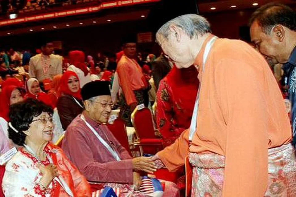 BERJABAT MESRA: Dr Mahathir (duduk) menyambut salaman Tun Abdullah di Perhimpunan Agung Umno semalam. - Foto BHM