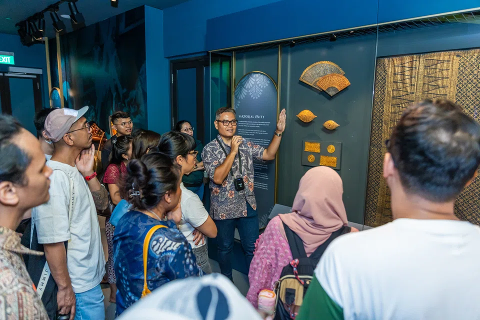 Pengurus Besar Taman Warisan Melayu (TWM), Encik Mohamed Hafiz Mohamed Shariff (tengah), menerangkan tentang artifak yang dipamerkan kepada kakitangan muzium semasa satu lawatan.