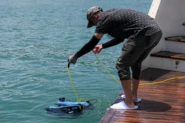 Penolong penyelidik Universiti Teknologi dan Reka Bentuk Singapura (SUTD), Encik Hoo Jun Jie, dari Makmal Visi dan Pembelajaran Robot Pelbagai Ejen (MARVL), keluarkan dron bawah air model BlueROV2 itu daripada kapal layar Star of the Sea di luar pantai Pulau Lazarus pada 11 Oktober 2024.
