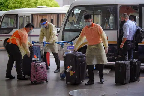 Kakitangan di Terminal 3, Lapangan Terbang Changi dilihat sedang mengendali bagasi yang dimiliki penumpang daripada sebuah pesawat yang telah tiba dari London pada 22 Disember 2020. - 