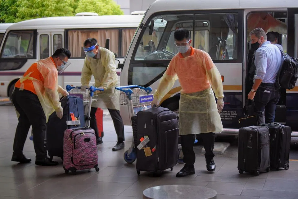 Kakitangan di Terminal 3, Lapangan Terbang Changi dilihat sedang mengendali bagasi yang dimiliki penumpang daripada sebuah pesawat yang telah tiba dari London pada 22 Disember 2020. - 