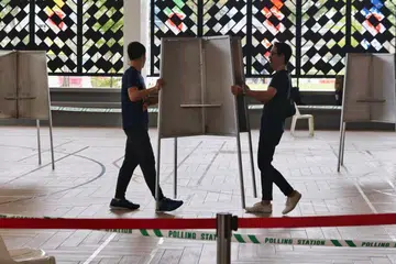 PERSIAPAN: Pegawai pilihan raya mengangkat dan meletakkan pondok mengundi di Pusat Mengundi yang terletak di Wisma Geylang Serai pada 31 Ogos 2023.