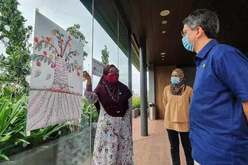CABANG KEHIDUPAN: Peserta kumpulan Keluarga Akrab (FEC), Cik Rohani Che Samsudin (kiri), menjelaskan 'Pohon Kehidupan' yang dilakar kepada Profesor Madya Dr Muhammad Faishal Ibrahim (kanan). Bersama mereka ialah seorang lagi peserta FEC, Cik Noor Zhah Jantan. - Foto BM oleh NURUL AIN RAZALI