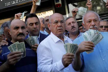 USAHA BERSAMA PERKUKUH LIRA: Golongan usahawan memegang dolar Amerika di hadapan pejabat tukaran mata wang asing di Ankara bagi menyahut seruan Presiden Turkey, Recep Tayyip Erdogan untuk menjual simpanan dolar dan euro mereka bagi memberi sokongan pada lira. - Foto REUTERS