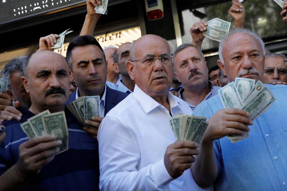 USAHA BERSAMA PERKUKUH LIRA: Golongan usahawan memegang dolar Amerika di hadapan pejabat tukaran mata wang asing di Ankara bagi menyahut seruan Presiden Turkey, Recep Tayyip Erdogan untuk menjual simpanan dolar dan euro mereka bagi memberi sokongan pada lira. - Foto REUTERS