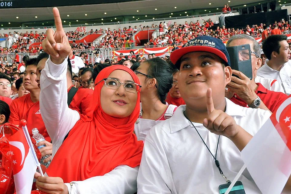 DITEMANI KAKAK: Pelajar berkeperluan khas, Encik Muhammad Nur Hakim Slamat, menyaksikan NDP secara langsung di Hab Sukan dengan ditemani kakaknya, Cik Nur Lina. - Foto KHALID BABA