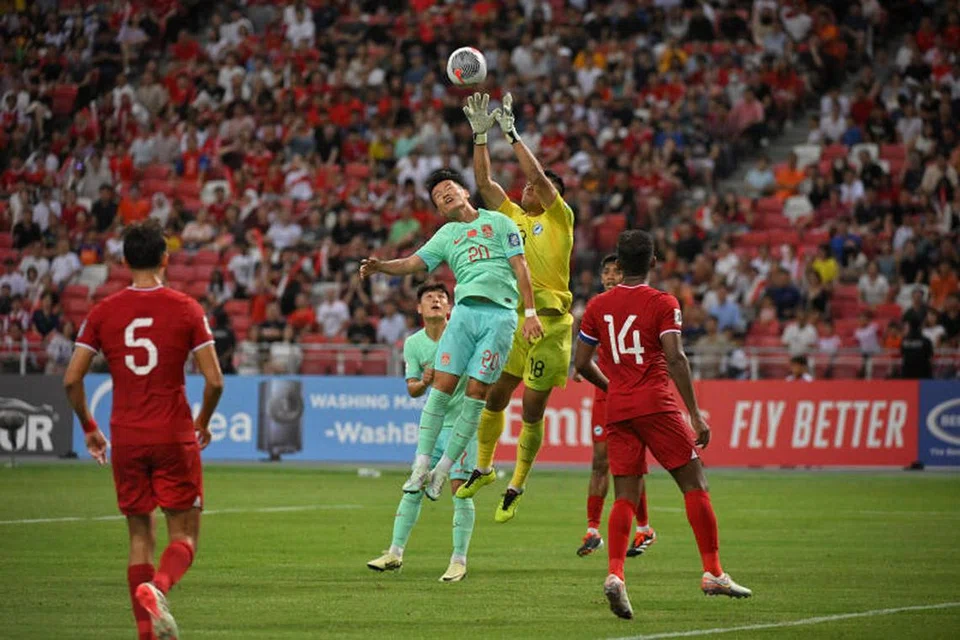 Penjaga gol Singapura, Hassan Sunny (kanan), berjaya menangkap bola daripada percubaan tandukan pemain China, Lin Liangming.