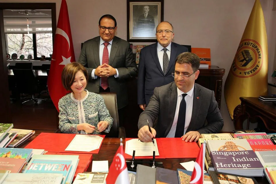KERJASAMA ANTARA PERPUSTAKAAN: Encik S. Iswaran (belakang, kiri), menyaksikan penandatanganan Memorandum Persefahaman (MOU) antara Lembaga Perpustakaan Negara (NLB) Singapura dan Perpustakaan Negara Turkey di Ankara pada 3 April lalu. Encik Iswaran diiringi Timbalan Menteri Kebudayaan dan Pelancongan Turkey, Profesor Ahmet Haluk Dursun (belakang, kanan). MOU tersebut bertujuan memperkukuh kerjasama dalam pendigitalan rekod, menurut kenyataan bersama Kementerian Perhubungan dan Penerangan (MCI) dan NLB. Perjanjian itu ditandatangani (duduk, dari kiri) Ketua Pegawai Eksekutif NLB, Cik Elaine Ng, dan Ketua Pengarah Perpustakaan dan Penerbitan Turkey, Encik Hamdi Tursucu. Beberapa buku di meja penandatangan itu merupakan antara 200 buku yang dihadiahkan NLB kepada Perpustakaan Negara Turkey. Pemberian buku itu menambah koleksi Perpustakaan Negara Turkey di Singapura, dan mempromosikan pemahaman tentang sejarah, masyarakat, budaya serta kesusasteraan Singapura. - Foto MCI