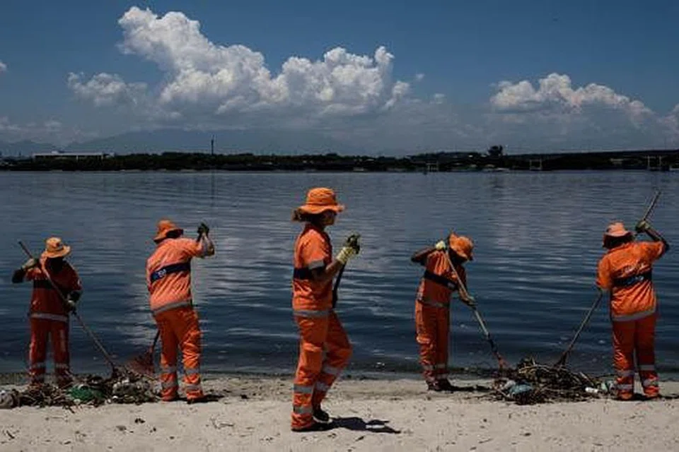 USAHA SAAT TERAKHIR: Sekumpulan pekerja berusaha mengutip sampah di Teluk Guanabara. - Foto AFP 