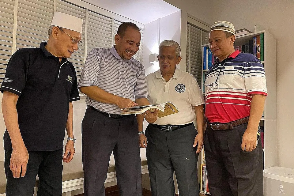 DIABADI DALAM BENTUK GAMBAR: Beginilah pemandangan sebahagian dewan serbaguna atau estal di tingkat 1 rumah kedai PPGC sebelum ia dikosongkan. Katil berbingkai besi yang digunakan dan menjadi aset kebanggaan setiap keluarga yang tinggal di PPGC. Ia ditinggikan sekitar empat kaki bagi membolehkan anak-anak kecil tidur di kolongnya. (Dari kiri) Encik Abdul Karim, Encik Borhan, Encik Abdul Sarip dan Encik Gazali menyingkap kenangan semasa membelek buku Ponthuk Bawean di Singapura. - Foto fail, MBS dan ISMAIL ALI