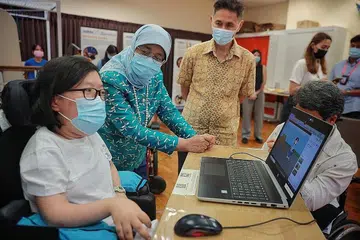 LAWATAN: Presiden Halimah Yacob (dua dari kiri) melihat animasi yang dibuat oleh Cik Jasmine Yau, semasa lawatannya ke Persatuan Distrofi Otot Singapura (MDAS) baru-baru ini. - Foto fail