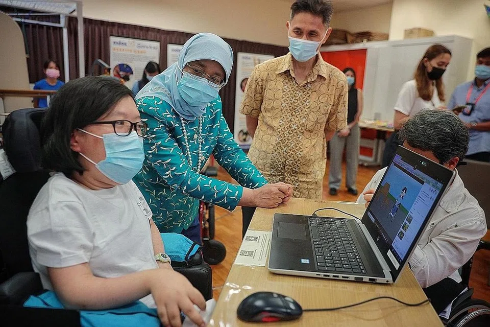 LAWATAN: Presiden Halimah Yacob (dua dari kiri) melihat animasi yang dibuat oleh Cik Jasmine Yau, semasa lawatannya ke Persatuan Distrofi Otot Singapura (MDAS) baru-baru ini. - Foto fail