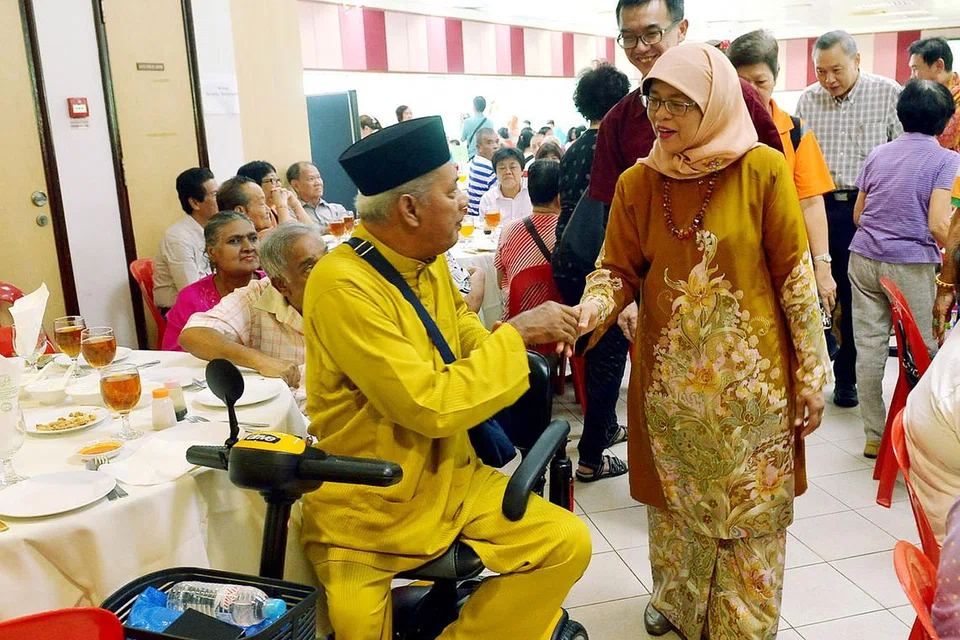 MERIAH RAYA BERSAMA: Cik Halimah Yacob berinteraksi dengan Encik Omar Ismail semasa acara sambutan Hari Raya beramai-ramai di Kelab Masyarakat Marsiling. - Foto TUKIMAN WARJI