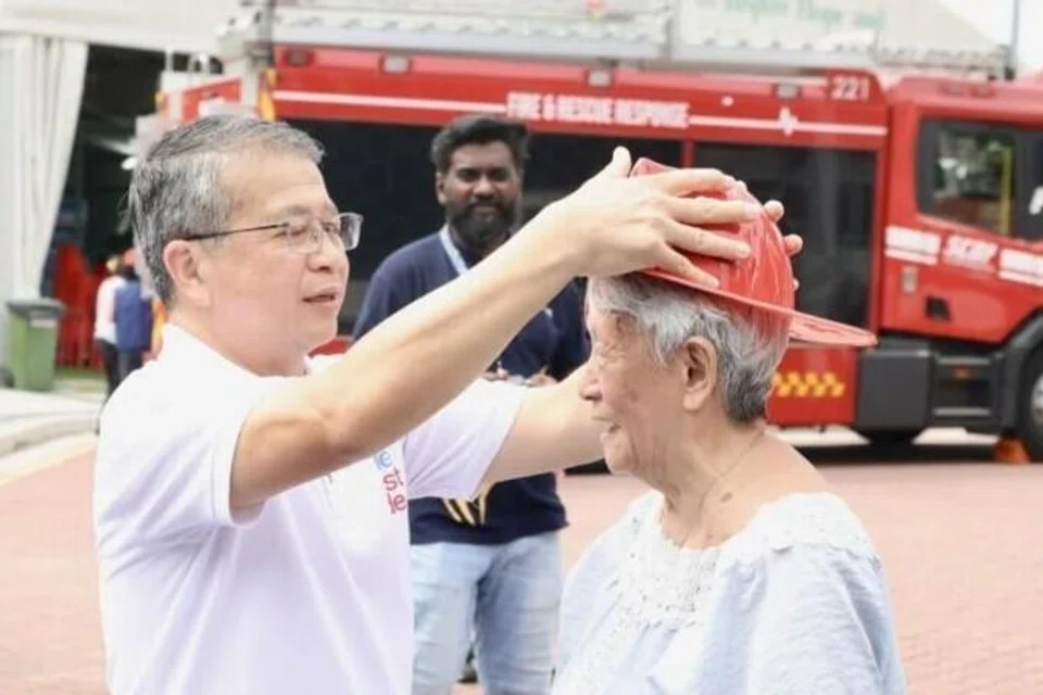 Menteri Undang-Undang merangkap Menteri Kedua (Ehwal Dalam Negeri), Encik Edwin Tong (kiri) bergaul dengan para penduduk dan memimpin ahli keluarga dalam usaha memadam kebakaran di stesen pemadaman kebakaran.