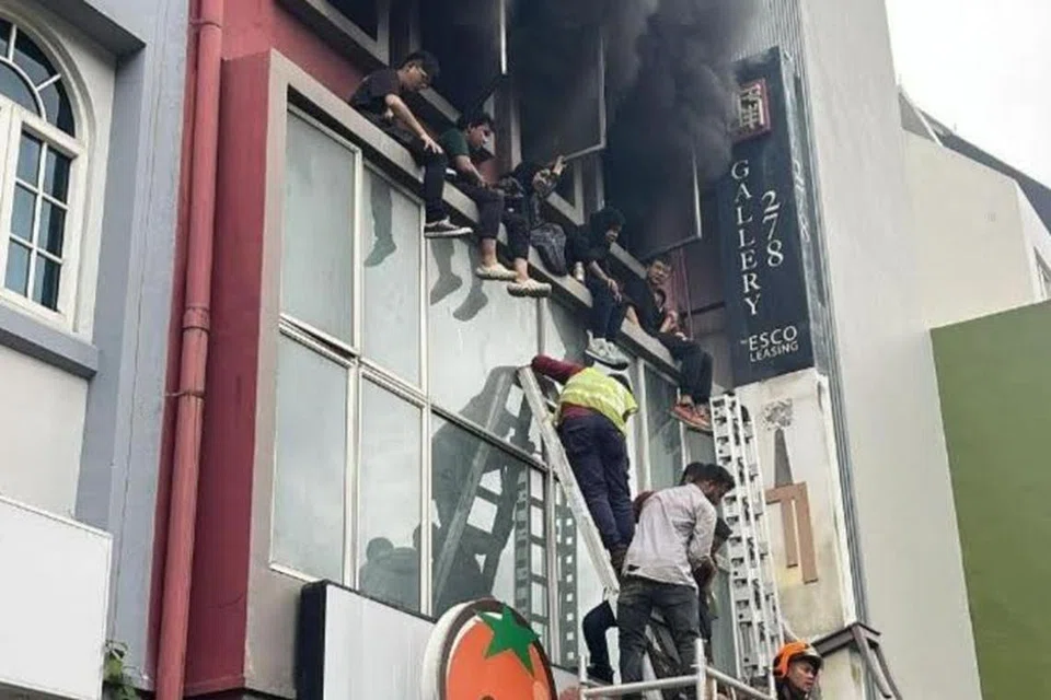Beberapa orang kebanyakannya remaja dilihat duduk di belebas bangunan, menunggu untuk diselamatkan. 