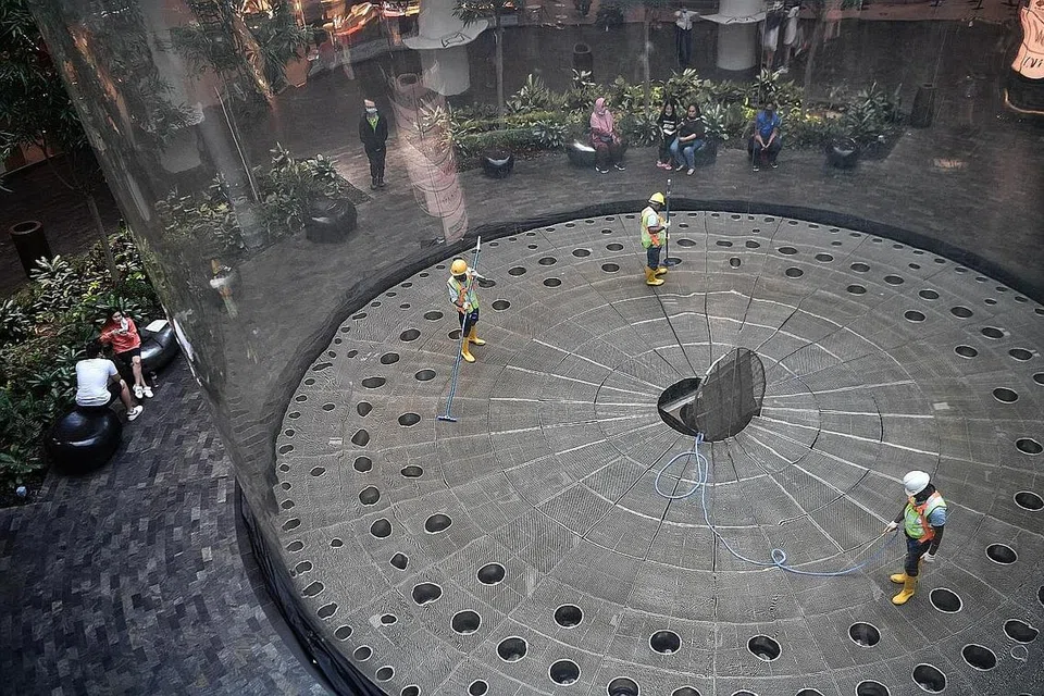 PEMBERSIHAN LANTAI: Pekerja harus menaiki tangga dan masuk ke dasar air terjun melalui lurang untuk membersihkan lantai dan mengeluarkan duit syiling dan objek lain yang mungkin terperangkap di situ.