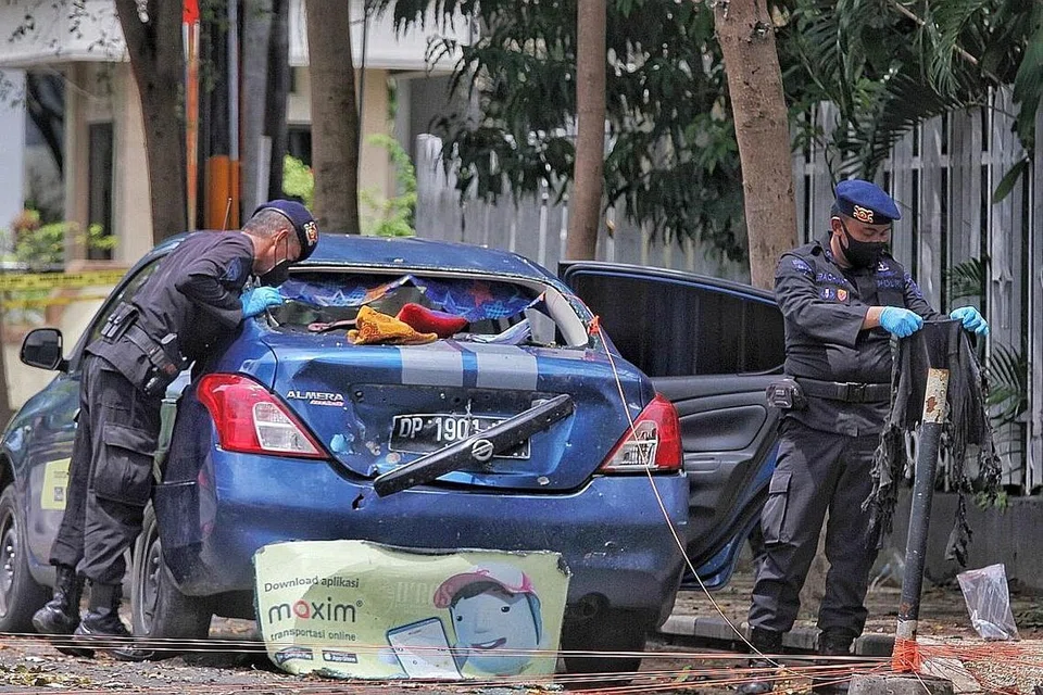 JALANKAN SIASATAN: Pegawai polis Indonesia mengumpulkan bukti dari sebuah kereta yang berada berdekatan gereja Katolik - sasaran percubaan pengeboman di Makassar. - Foto AFP