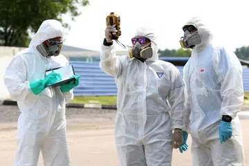 PERIKSA UDARA: Pegawai yang memakai kelengkapan perlindungan memeriksa mutu udara di Pasir Gudang pada 25 Jun 2019.