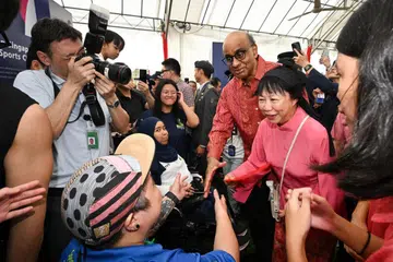 Presiden Tharman Shanmugaratnam (tiga dari kanan) dan isterinya, Puan Jane Ittogi, beramah dengan atlet paralimpik boccia, Cik Nurulasyiqah Mohammad Taha (tengah, bertudung), dan perenang paralimpik, Cik Theresa Goh (memakai topi), di khemah utama Rumah Terbuka Istana sempena Tahun Baru Cina pada 2 Februari.