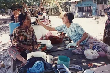 (kiri) Cik Ninah Gap, nenek kepada pengasas Orang Laut SG, Encik Firdaus Sani disuap oleh seorang penduduk Pulau Semakau, Cik Ru.