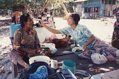 (kiri) Cik Ninah Gap, nenek kepada pengasas Orang Laut SG, Encik Firdaus Sani disuap oleh seorang penduduk Pulau Semakau, Cik Ru.