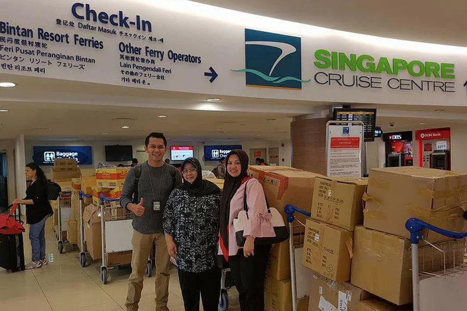 BARANGAN YANG BAKAL DIDERMA: Sumbangan barangan rakyat Singapura dilihat dibungkus rapi dan dibawa ke Terminal Feri Tanah Merah untuk dihantar ke Aceh. Cik Noor Lizah Nurdin (tengah) yang menyelaraskan usaha bantuan di sini bergambar bersama pegawai pemerintah dari Tanjung Pinang, Cik Leni Marlina (kanan) dan Pak Andi.- Foto SITI NURANI SALIM 