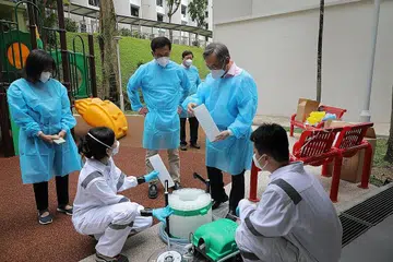 ALAT KUMPUL SAMPEL AIR SISA: Encik Gan Kim Yong (dua dari kanan) dan Encik Ong Ye Kung (tengah) ditunjukkan bahagian dalam alat autosampler yang digunakan untuk mengumpul air sisa dari lurang secara berkala. - Foto BH oleh ONG WEE JIN