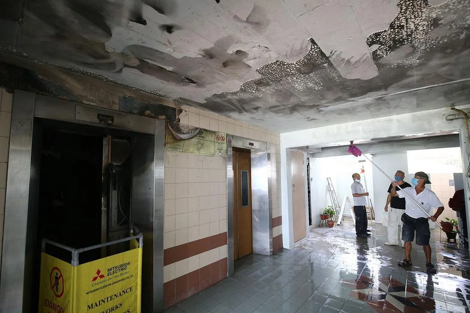 DIBERSIHKAN: Beberapa pekerja dilihat mencuci tembok dan siling lobi lif tingkat dua di Blok 537 Woodlands Drive 16 yang dijilat api menyusuli satu kes kebakaran yang berpunca daripada PMD. - Foto LIANHE ZAOBAO