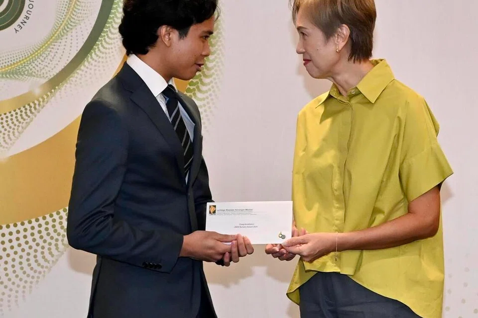 Encik Hakim (kiri) menerima geran $10,000 dalam membantu kos perbelanjaan universitinya. Bersama dalam gambar ialah Menteri Penerangan dan Pembangunan Digital, Cik Josephine Teo.