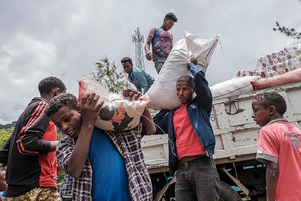 BANTUAN MAKANAN: Penduduk yang kehilangan tempat tinggal akibat perang di utara Habsyah, mengangkut makanan dan bekalan dari sebuah trak, yang disediakan oleh penduduk tempatan di Sekolah Addis Fana di mana mereka ditempatkan buat sementara, di kota Dessie, Habsyah, pada 23 Ogos lalu. - Foto AFP